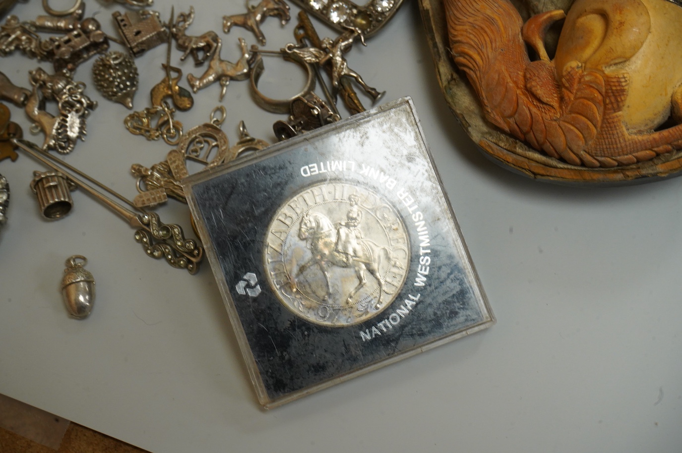 A small collection of silver and white metal charms, including Holy Bible, Penny Farthing, hedgehog and squirrel, together with a silver compact and ashtray, a silver and paste brooch, nut vesta, pipe, etc.